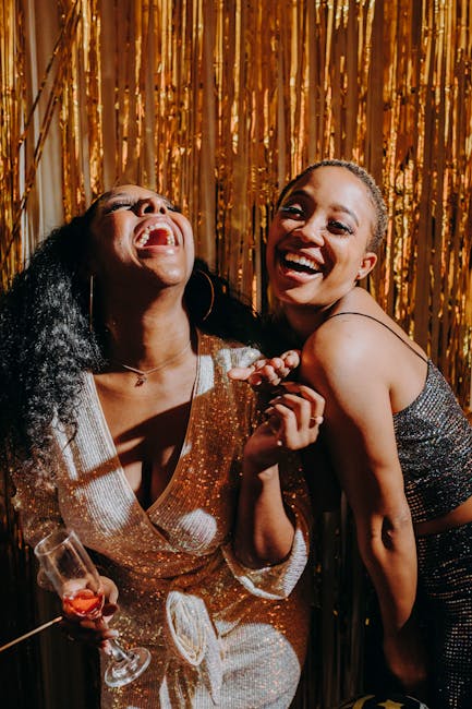 pexels-photo-6224736-6224736 Two women laughing and enjoying a party with a festive golden backdrop.